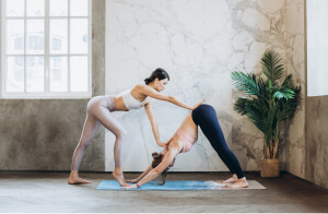 Two students in a yoga class work with each other to stretch.