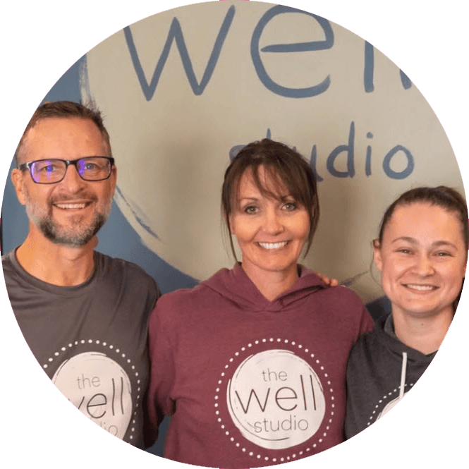Well Studio founders, Ron & Stacy, smile and pose with manager Gillian in front of Well Studio logo.