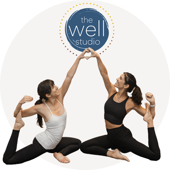 Two members of Well Studio in a yoga pose holding hands above heads to form a heart over studio logo.