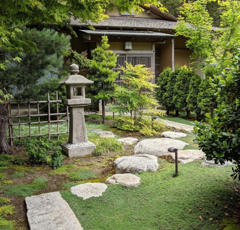 Exterior path with stepping stones surrounded by moss and trees that lead to Zen Center entrance.