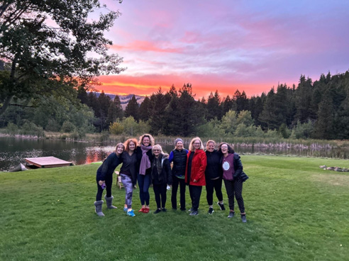 Well Studio members gather in front of lake at 2024 Feathered Pipe Ranch Retreat in Montana.