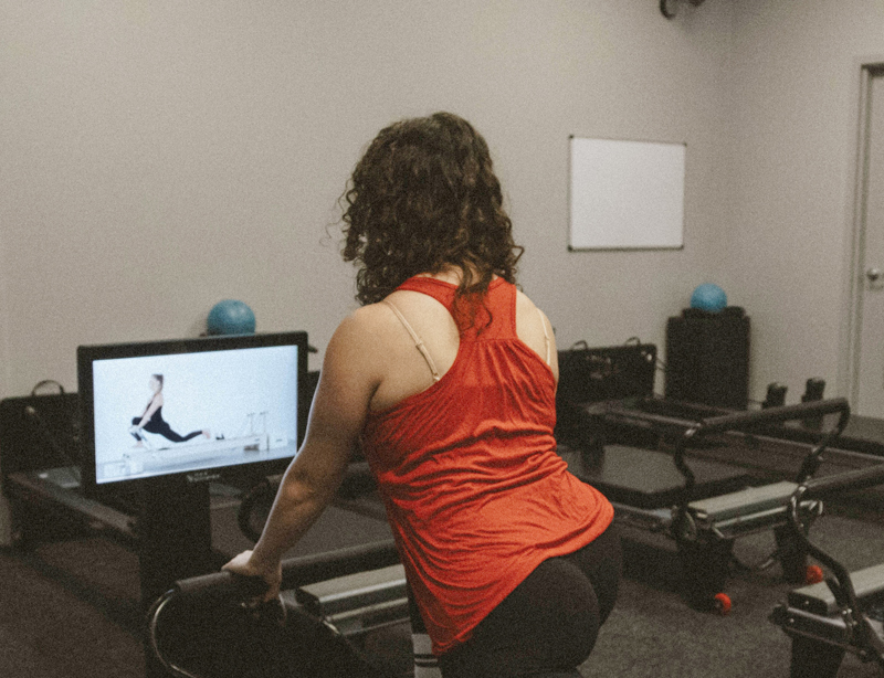 A female Well Studio member using an On-Demand Pilates Reformer called KioskPro.