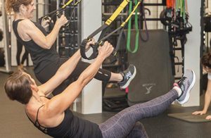 Students using weight resistance machines to strengthen upper body muscles.